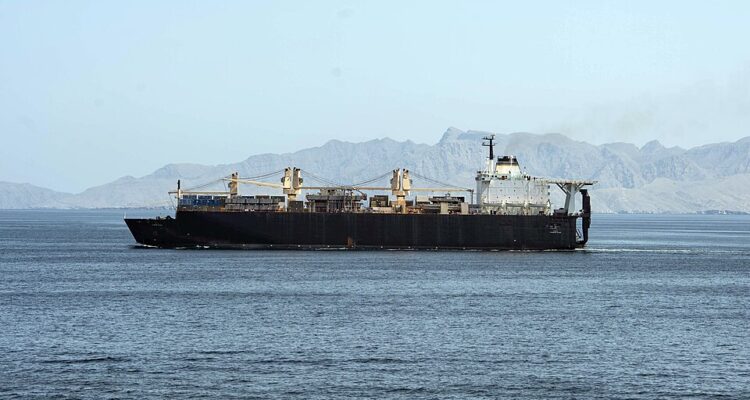 USNS PFC Dewayne T. Williams sailing through the Strait of Hormuz with mountains behind it.
