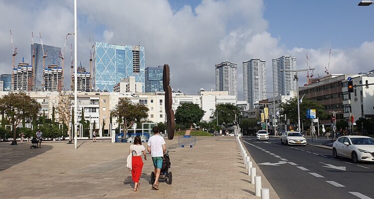 Tel Aviv towers and construction cranes seen above Habima Square, with pedestrians and traffic in the foreground.